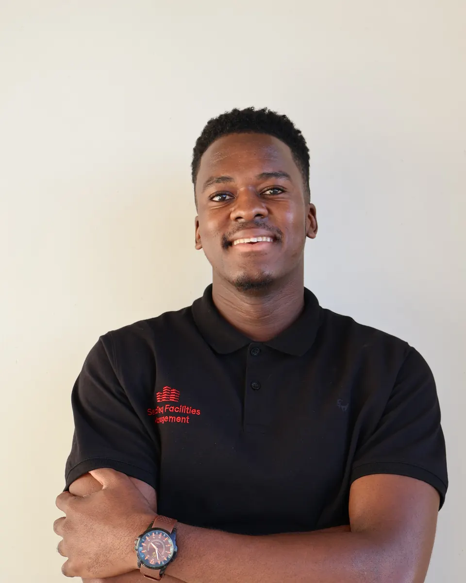A smiling SecaTeq FM technician in a black SecaTeq shirt, with his arms folded.