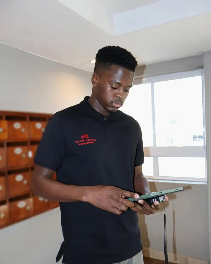 A SecaTeq FM technician checking a tablet in a building lobby.