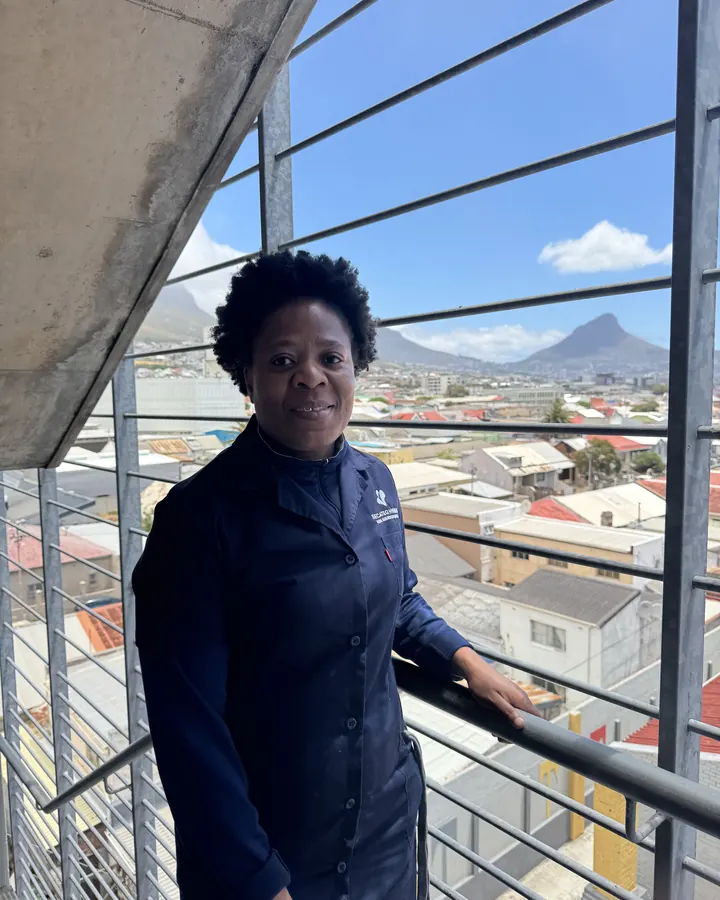 A smiling SecaTeq Hygiene team member on a stairwell landing, with the city behind her.
